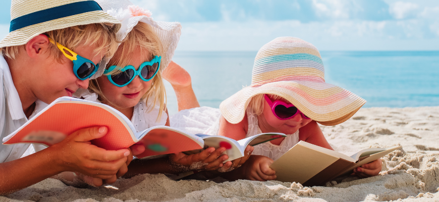 Bild på barn som läser böcker på sandstrand